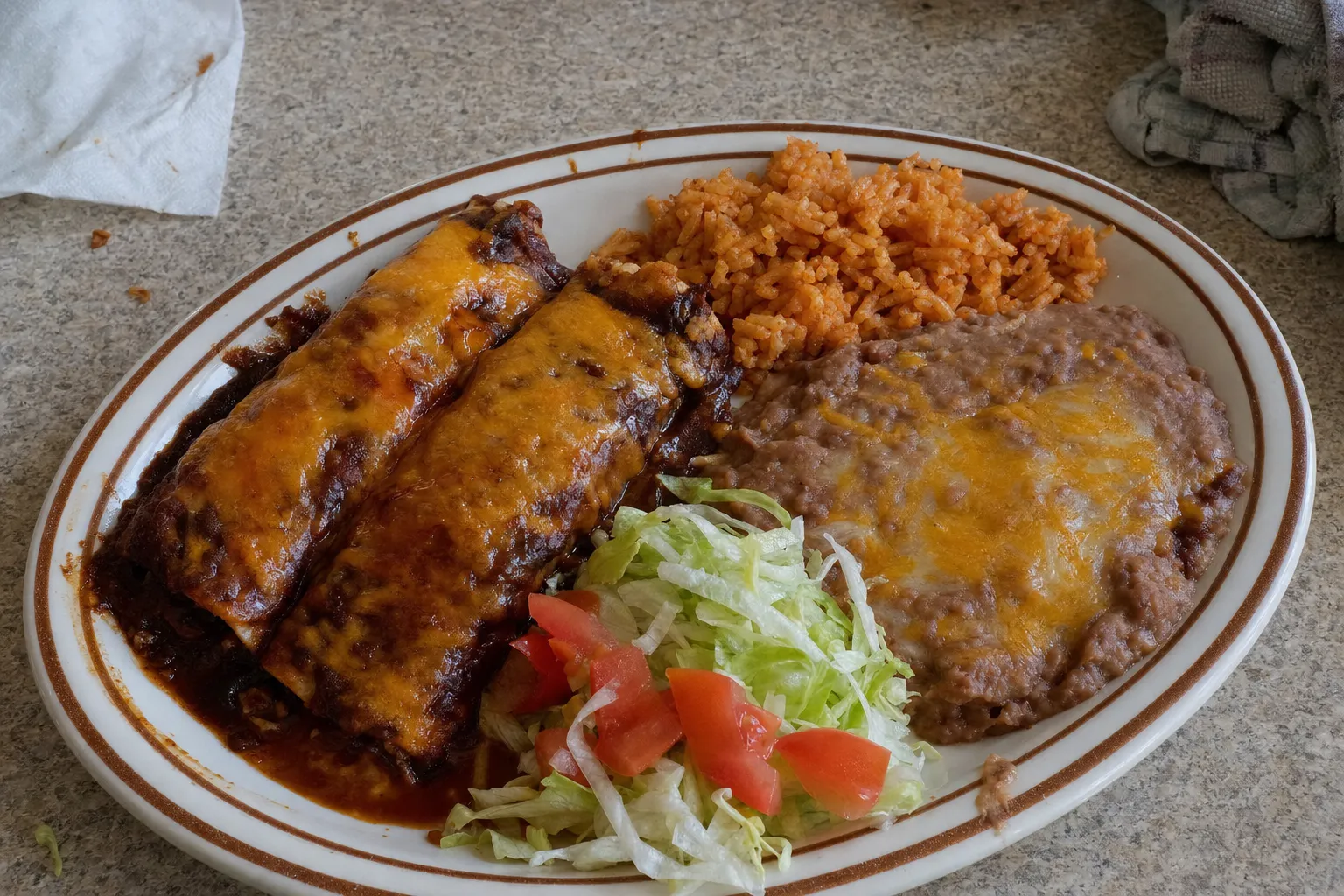 エンチラーダ2本に、メキシカンライス、チーズをのせたリフライドビーンズ、レタスとトマトを盛ったコンビネーション・プレート
